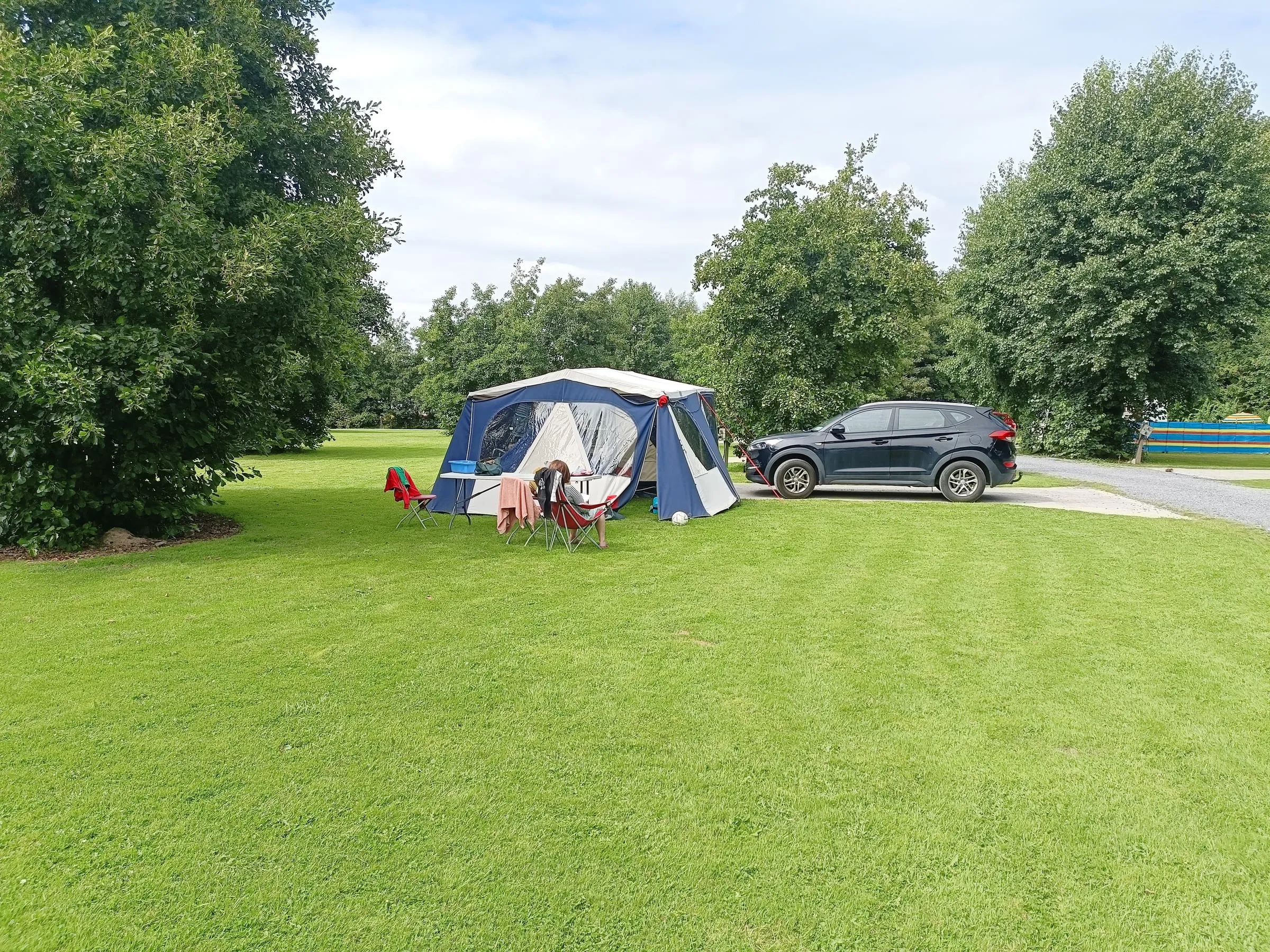 A family tent pitched on the wide lawn of The Apple Camping and Caravan Park